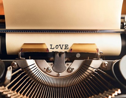 View from above of a retro typewriter equipped with 'love' word paper sheet, representing