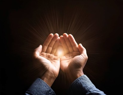 Image of open hands embracing a radiant light source, embodying concepts of hope, spirituality, and