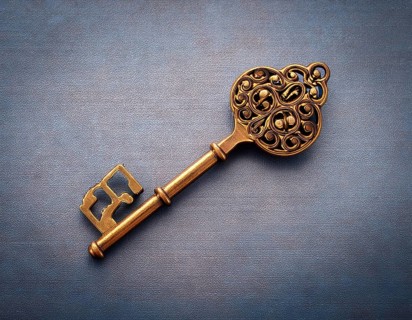 The intricately designed antique gold key lies on a dark leather surface, exuding mystery and