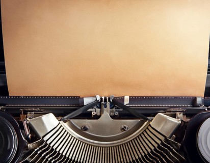 View from above of a retro typewriter equipped with a blank paper sheet, representing creativity,