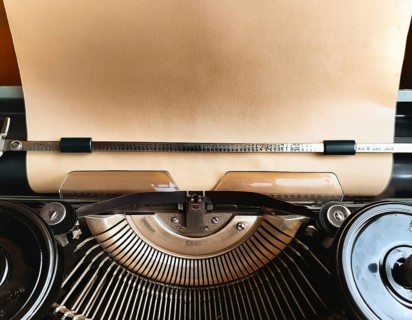 View from above of a retro typewriter equipped with a blank paper sheet, representing creativity,