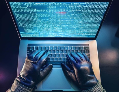 Cybersecurity threat depicted by gloved hands operating a computer, commands displayed on the