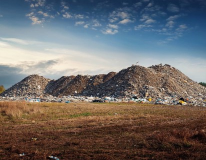 A scenic evening view of a large landfill site with piles of collected waste surrounded by open