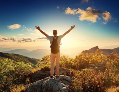 A serene scene of a person on a mountain summit, watching the sunrise over misty valleys, conveys