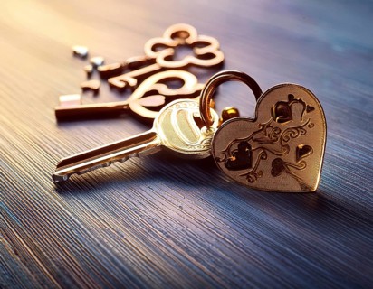 Elegant heart-shaped locket and intricate key on textured surface, surrounded by glowing hearts. An