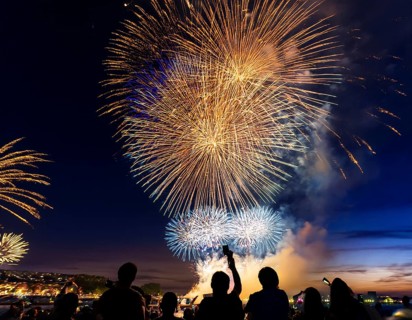 Thrilling fireworks illuminate the dark sky as a crowd gathers to enjoy the dazzling display,