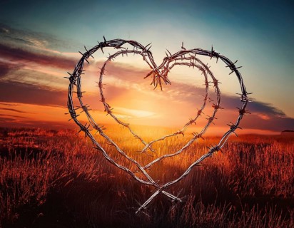 A symbolic depiction of a red heart entwined in barbed wire, set against a blurred warm-toned bokeh