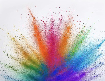 Vibrant and energetic multicolored powder explosion captured against awhite background. Evoking