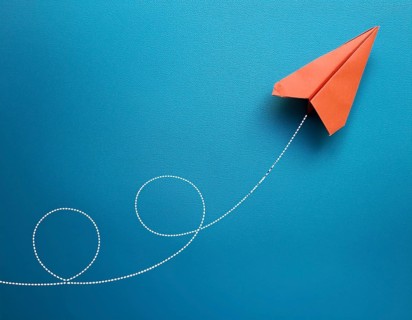Simple artwork depicting a stylized paper airplane soaring gracefully with a looped trajectory.