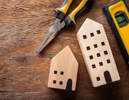 A detailed layout of miniature wooden houses accompanied by various tools on a textured wooden