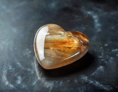A heart-shaped gemstone with vivid colors placed on a textured surface, capturing an elegant and
