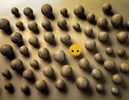 Wooden balls feature faces, one smiling among sad expressions, representing positivity or
