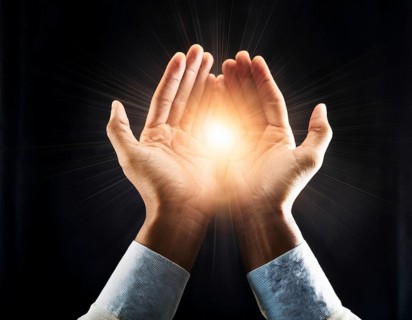 Hand holding light ray in the darkness, hope concept. Light in hands. Freedom and spirituality