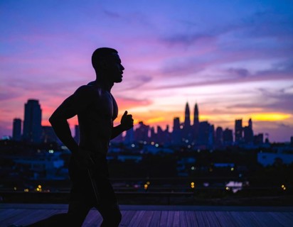 A cinematic silhouette of an athletic man running, representing fitness, endurance, wellness, and