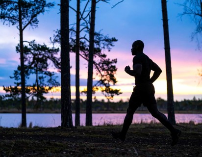 A cinematic silhouette of an athletic man running, representing fitness, endurance, wellness, and