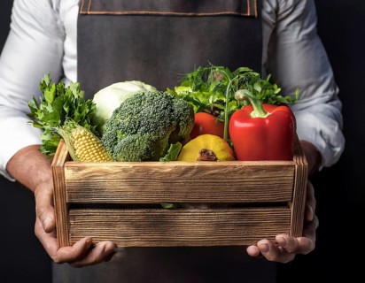 Man holding wooden crate with vegetables. Wooden box filled with fresh food products and ready for