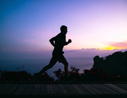 A cinematic silhouette of an athletic man running, representing fitness, endurance, wellness, and
