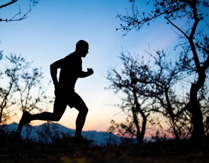 A cinematic silhouette of an athletic man running, representing fitness, endurance, wellness, and