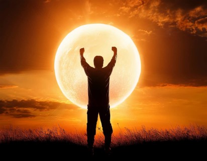 Man silhouette against giant glowing sun symbolizing inspiration, destiny, reflection, cosmic