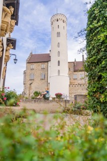 Woman sitting quietly in a castle garden in front of a high tower, Lichtenstein Castle,