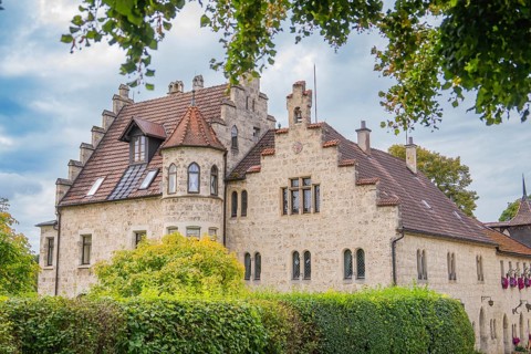 An old building with a red tiled roof and many windows, surrounded by trees, Lichtenstein Castle,