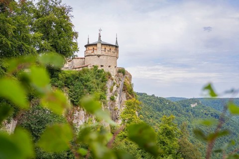 An impressive castle perched high on a cliff with sweeping views over the green landscape,