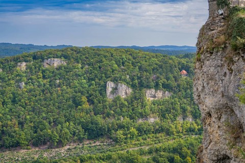 Lush forest landscape with steep rock faces and a vast green panorama in the distance, Lichtenstein