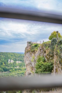 Spectacular cliff view with green landscape and wide sky in the background, captured from a railing