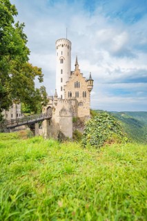 Medieval castle on a grassy cliff, surrounded by a picturesque landscape and dramatic sky,