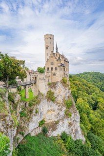 Castle stands impressively on a green cliff under a blue sky, Lichtenstein Castle, Lichtenstein,