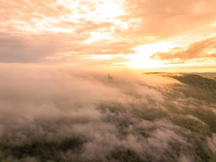 Aerial view of a fog-covered forest at sunset with dramatic sky, Lichtenstein Castle, Lichtenstein,