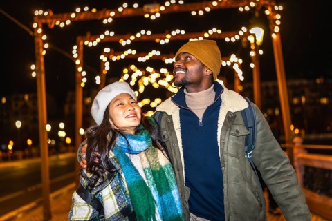 Multiethnic couple enjoying the enchanting glow of christmas lights while strolling through a