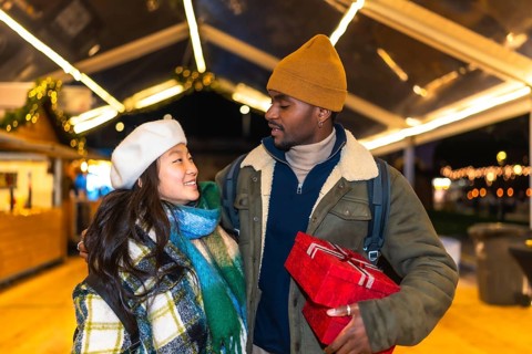 Young multiethnic couple exchanging christmas gifts and enjoying christmas time at a christmas