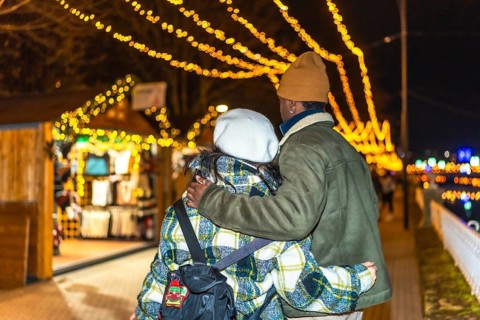 Young multiethnic couple walking hand in hand, sharing warm hugs amidst the glowing lights of a