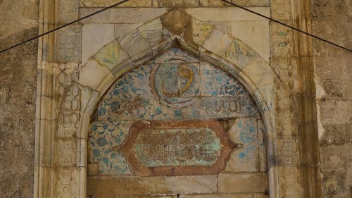 Decorated arch with faded inscriptions and ornaments on a stone background, Recep Pasha Mosque, Old
