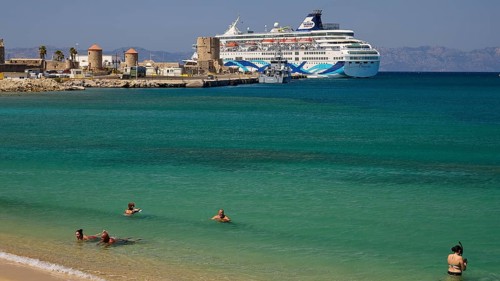 Large cruise ship in the harbour near a beach with turquoise water and bathers, Sachtouri Beach,