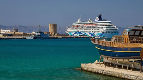 Coastal view with traditional boat and cruise ship in the harbour in sunny weather, Rhodes Old