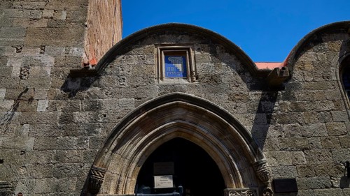Kasteliani Public Library, Italian coat of arms, Historic stone gate under a clear blue sky, Rhodes