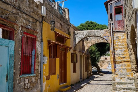 Narrow alley with old houses, yellow facades and colourful windows, Jewish Quarter, Rhodes Old
