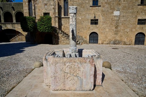 Medieval sandstone fountain with stone column in a historic ruin in the sunshine, Rhodes Old Town,