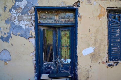 Weathered door and shutters on an old, dilapidated building with peeling paint, Rhodes Old Town,