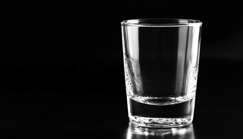 Black Background Showcasing A Lone, Empty Glass In The Foreground. The Stark Contrast Between The