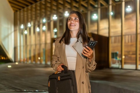 Young businesswoman walking confidently at night in an urban setting, carrying a briefcase and