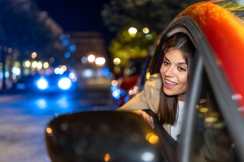 Woman looking out car window enjoying a vibrant city night with blurred lights creating bokeh,