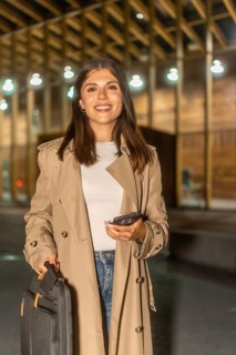 Young businesswoman traveling and commuting, holding a smartphone and briefcase, smiling while