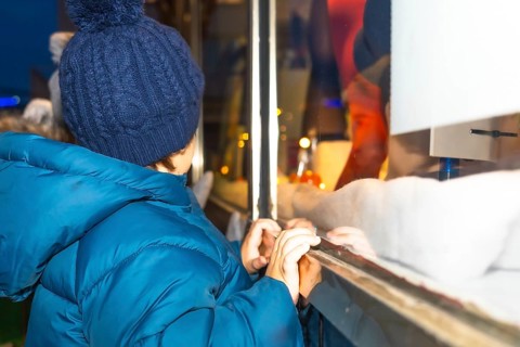 Curious child admiring a festive christmas window display in bayonne, france, during the magical
