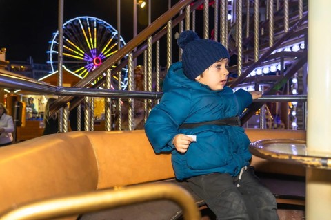 Young child enjoying a carousel ride at a vibrant christmas market in bayonne, france, creating a