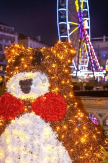 Festive christmas bear decoration shines brightly in bayonne, france, with a ferris wheel adding to