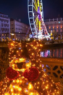 Luminous christmas bear decoration shining brightly in bayonne, france, with a ferris wheel and
