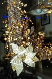 Festive christmas wreath adorned with golden and white poinsettia, berries, and string lights